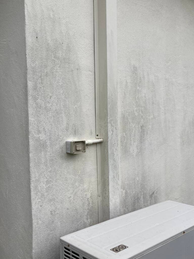Rendered exterior wall with mould staining before cleaning